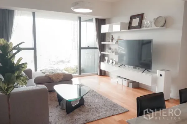Condominium for rent in Sathon, Bangkok - Bright lounge with sectional sofa, glass coffee table and balcony access