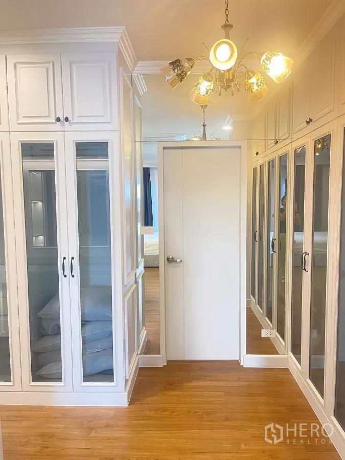 Detached House for rent in Bang Phli, Samut Prakan - Walk-in closet corridor with glass-front wardrobes and chandelier lighting.