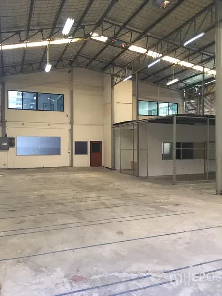 Warehouse for rent in Suan Luang, Bangkok - Spacious warehouse interior with high ceiling, steel trusses, concrete floor, and mezzanine offices with windows.