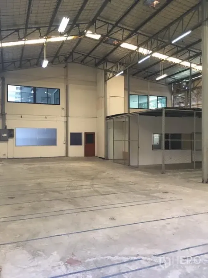 货栈 出租在Suan Luang, Bangkok - 仓库内部空间开阔，钢结构高挑屋顶，混凝土地面，带窗的夹层办公室。