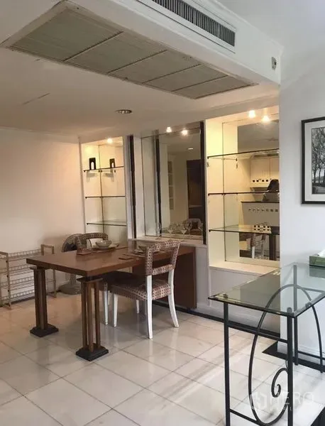 公寓 出租在Khlong Toei, Bangkok - 明亮的用餐角落，木质餐桌、藤椅，带玻璃展示柜与厨房传菜窗。