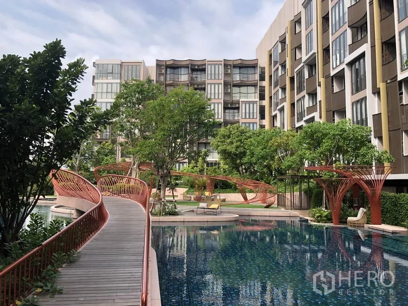 Condominium for rent or sale in Watthana, Bangkok - Resort-style pool with curved footbridge and garden pavilions at the condominium.