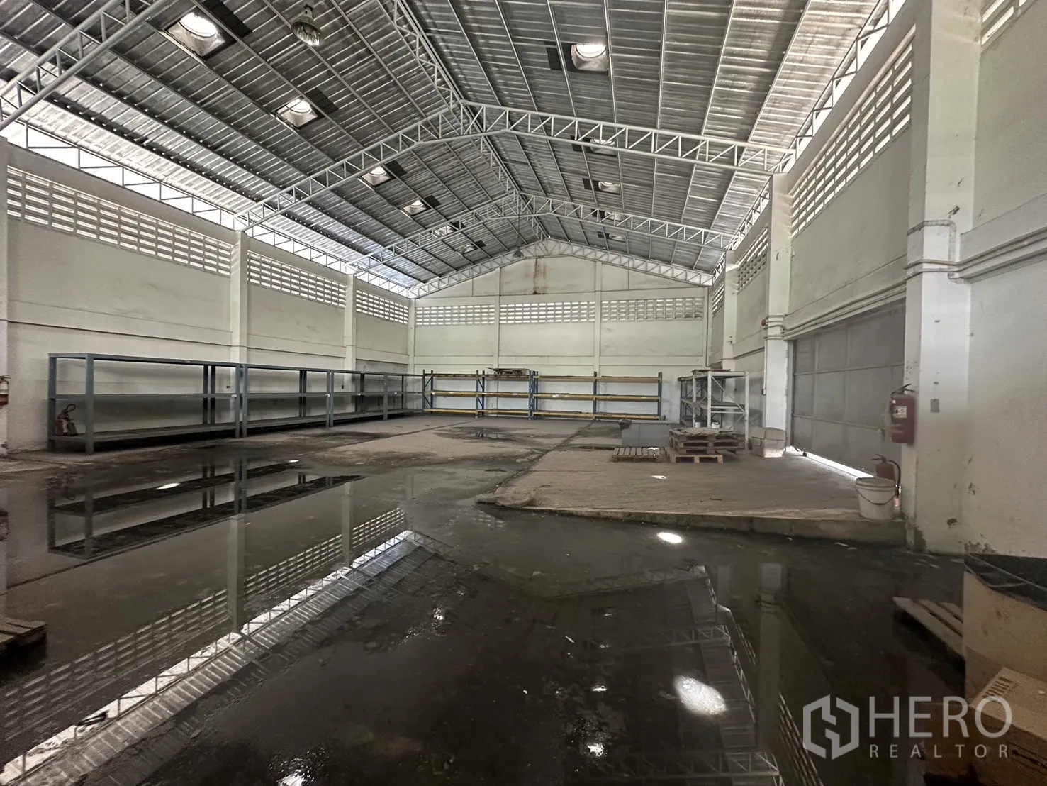 Factory for rent or sale in Prawet, Bangkok - Warehouse bay with racking, roller shutter doors and high roof.