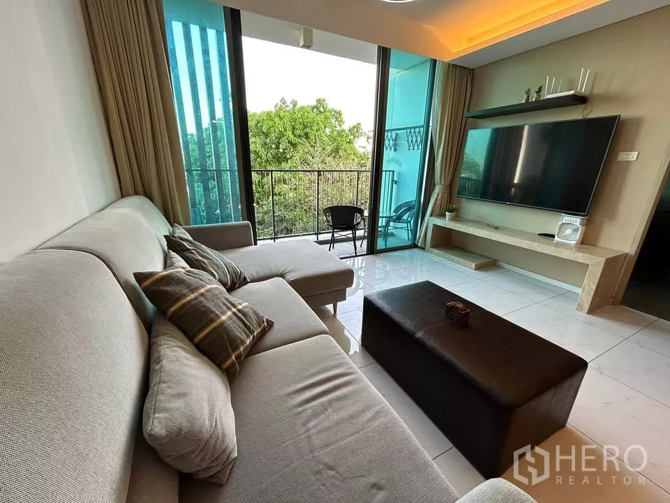 公寓 出租在Watthana, Bangkok - L型沙发对着电视，推拉玻璃门连通阳台与灯槽天花