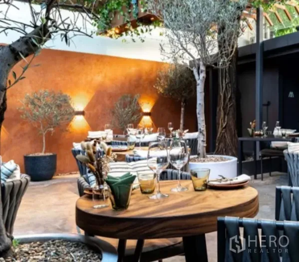 Retail Space for rent in Yan Nawa, Bangkok - Covered garden patio dining area with wooden tables, trees, and ambient wall lights.