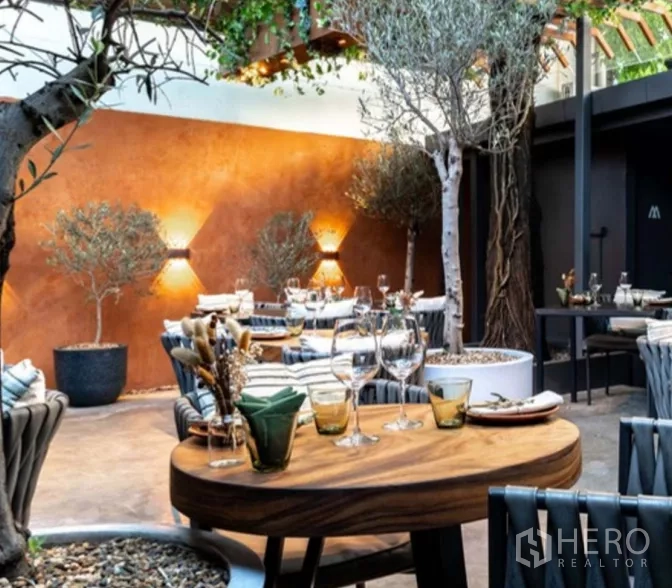 Retail Space for rent in Yan Nawa, Bangkok - Covered garden patio dining area with wooden tables, trees, and ambient wall lights.
