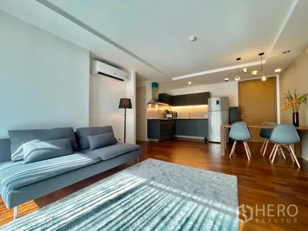 Condominium for rent or sale in Khlong Toei, Bangkok - Bright living room with sofa, rug, and full kitchen in open layout.
