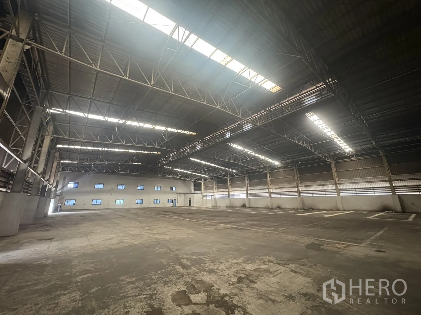 Factory for rent or sale in Samut Prakan - Spacious warehouse interior with high steel truss roof and skylights.
