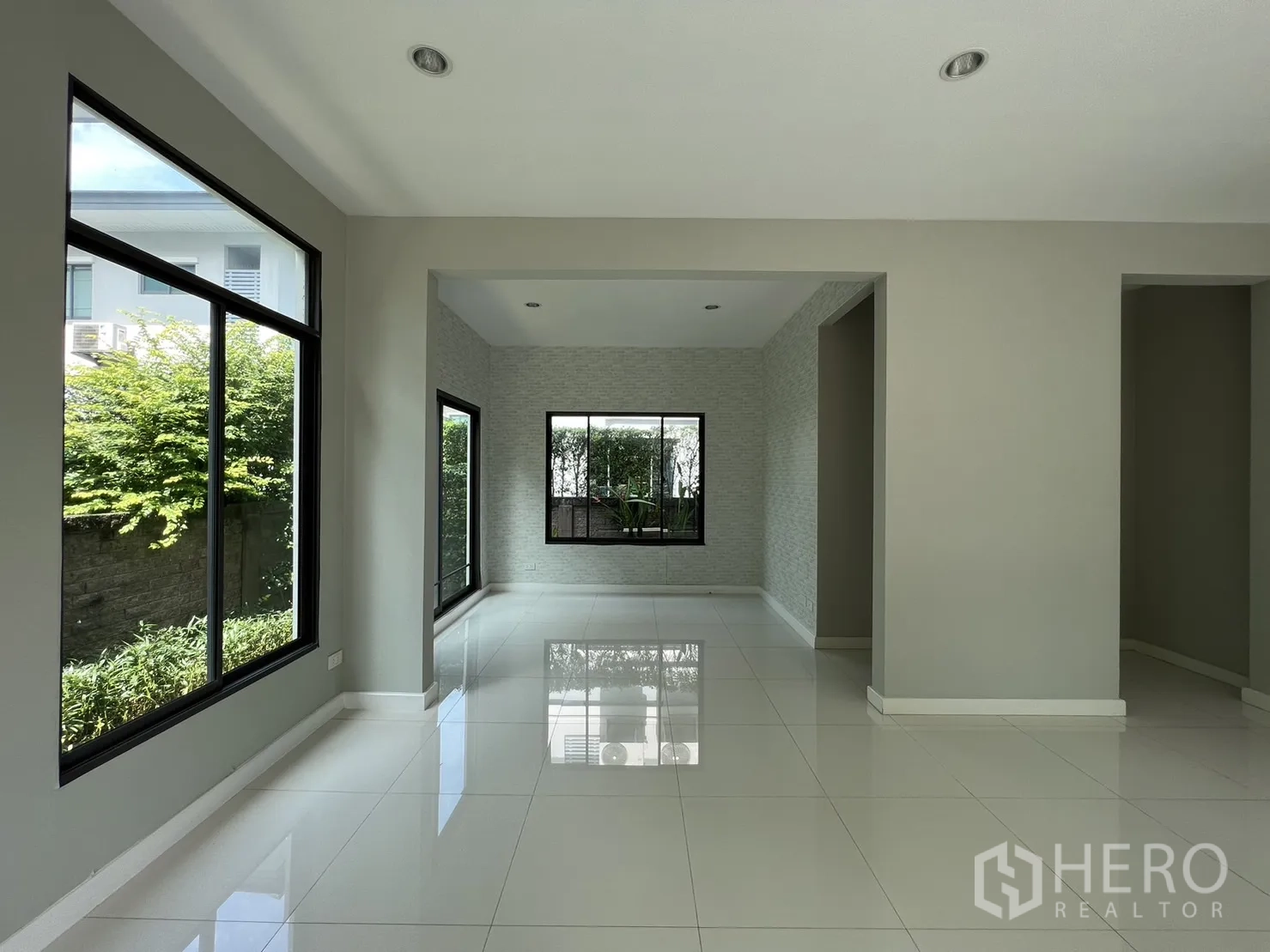 Detached House for sale in Suan Luang, Bangkok - Dining nook beside floor-to-ceiling windows overlooking green hedges.