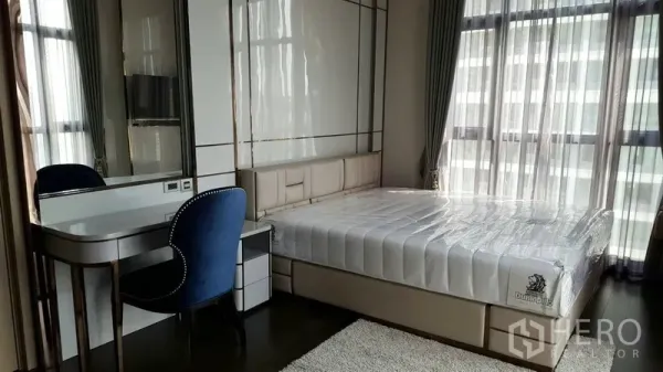 Condominium for rent in Watthana, Bangkok - Bedroom with a large bed, vanity desk and full-height windows with sheer curtains.