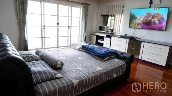 独立式住宅 出租在Prawet, Bangkok - 主卧宽敞，配大床、壁挂电视，推拉玻璃门通向阳台。