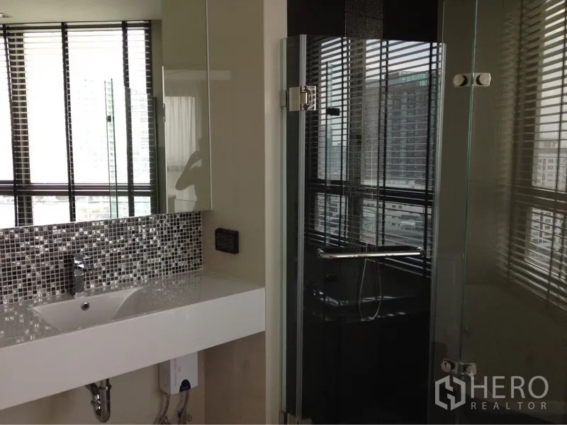 Condominium for rent in Khlong Toei, Bangkok - Contemporary bathroom featuring a glass shower enclosure, mosaic backsplash and wide vanity.
