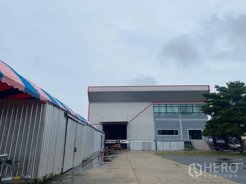 Factory for rent or sale in Lam Luk Ka, Pathum Thani - Industrial factory exterior in Lam Luk Ka with a wide driveway and loading bay.