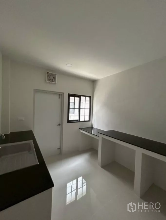 Detached House for rent in Bang Phli, Samut Prakan - Separate kitchen with black countertops, sink, window and service door.
