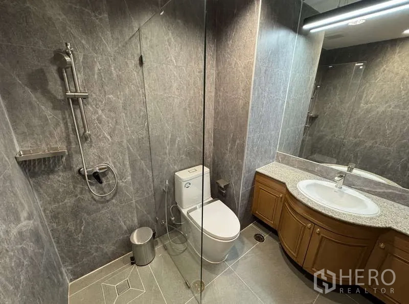 Condominium for rent - Bathroom with glass shower, curved granite vanity and large mirror.