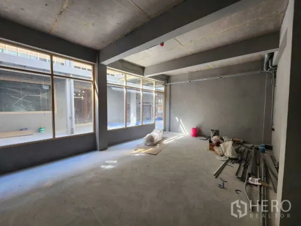 Retail Space for rent in Watthana, Bangkok - Bright open‑plan retail space with floor‑to‑ceiling windows and grey concrete finishes.