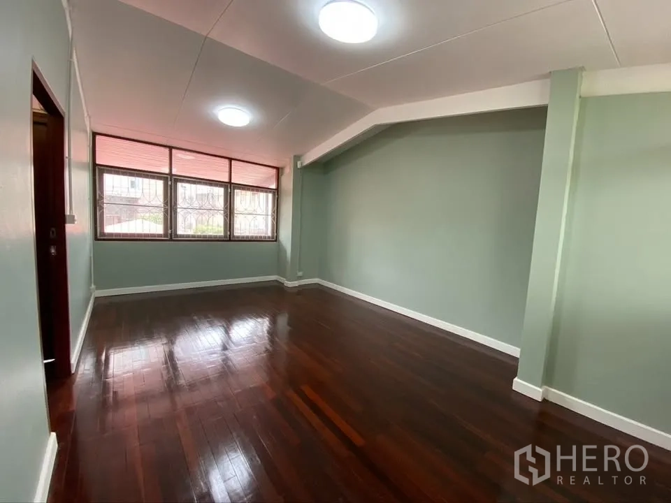 Detached House for rent in Suan Luang, Bangkok - Spacious bedroom with green walls, glossy wood flooring, and windows.
