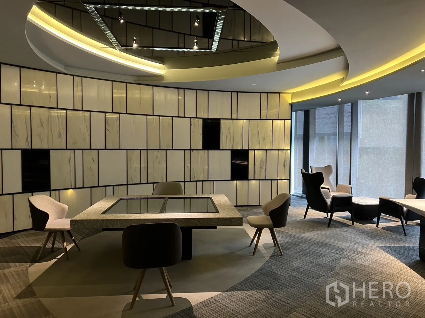 Retail Space for rent in Watthana, Bangkok - Modern retail showroom interior with curved ceiling lighting, paneled feature wall, carpet tiles and lounge seating around a central display table.