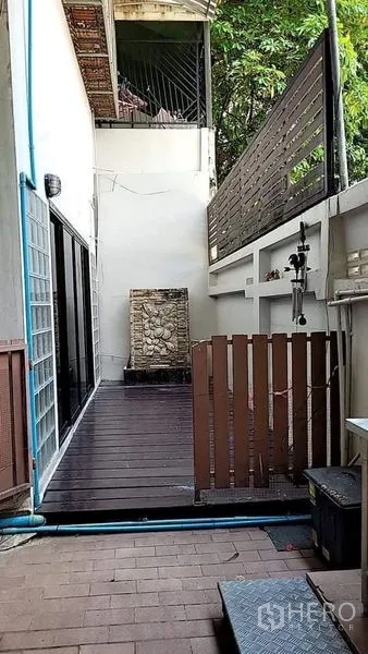 บ้าน ให้เช่า - ทางเดินลานด้านข้างปูไม้สีเข้ม มีรั้วบังสายตาและน้ำตกผนัง