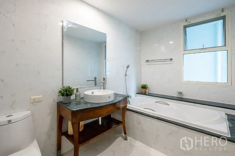 公寓 出售在Watthana, Bangkok - 白色大理石风格卫浴，设浴缸、台盆与采光窗。
