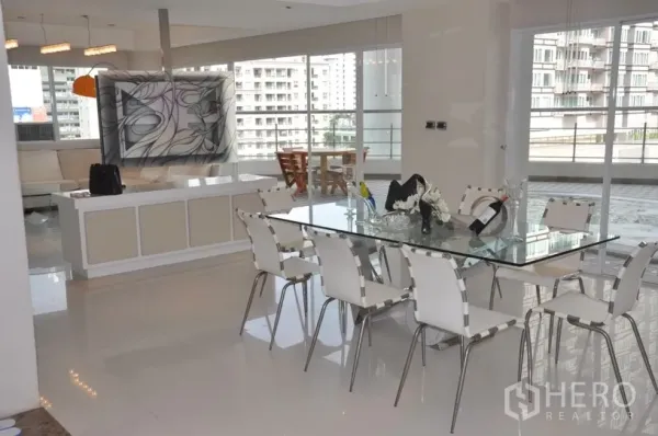 Condominium for rent in Khlong Toei, Bangkok - Modern dining area with glass table for eight, floor‑to‑ceiling windows and access to the wraparound terrace.