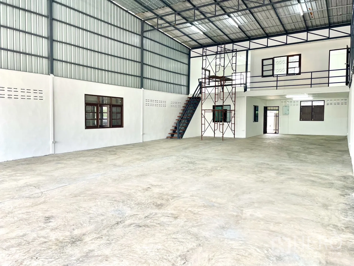 Warehouse for rent in Lam Luk Ka, Pathum Thani - Bright high-ceiling warehouse interior with concrete floor, steel frame, mezzanine offices and stair access.