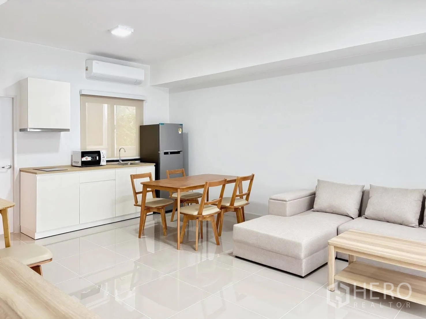 Townhouse for rent in Bang Phli, Samut Prakan - Bright open-plan living area with kitchenette, wooden dining set, and L-shaped sofa.