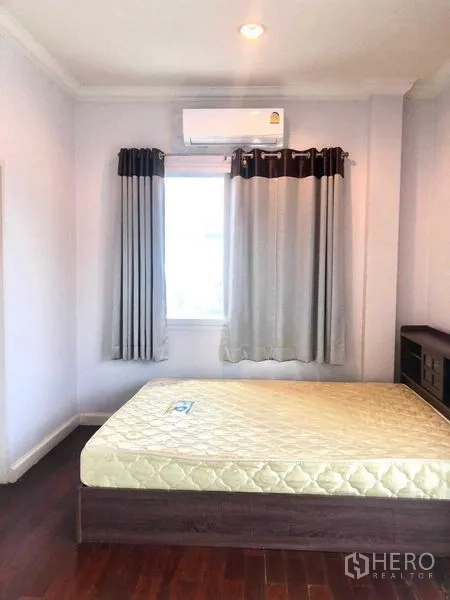 独立式住宅 出售在Lat Krabang, Bangkok - 卧室一角配窗帘、壁挂空调与床铺。