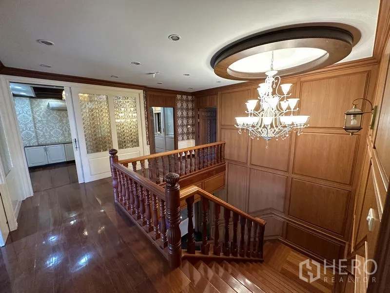 Detached House for sale in Lam Luk Ka, Pathum Thani - Wood staircase and chandelier on upper landing with wall paneling