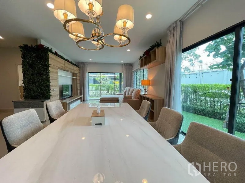บ้าน ขายในPak Kret, Nonthaburi - ห้องทานอาหาร โต๊ะหินอ่อน โคมแชนเดอเลียร์ และหน้าต่างสูงมองเห็นสวน