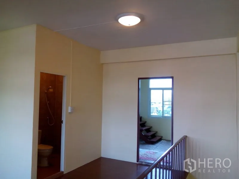 Shophouse for rent in Phra Khanong, Bangkok - Landing area showing bathroom entrance and windows with stairs beyond.