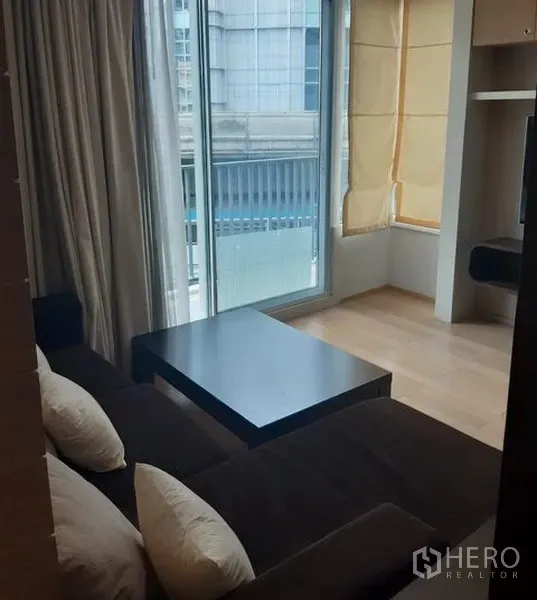 公寓 出租在Khlong Toei, Bangkok - 客厅设落地窗、咖啡桌与通往阳台的推拉门。