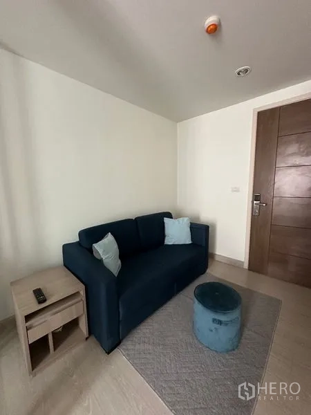 公寓 出售在Khlong Toei, Bangkok - 入户一侧的客厅，海军蓝沙发与脚凳，木质入户门。
