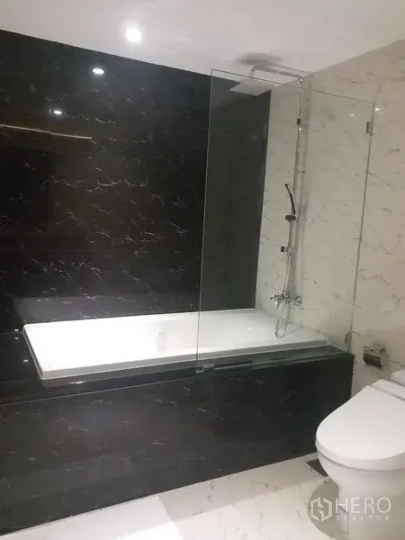 公寓 出租在Bang Rak, Bangkok - 现代卫浴，带浴缸与玻璃隔断，黑白大理石装饰。