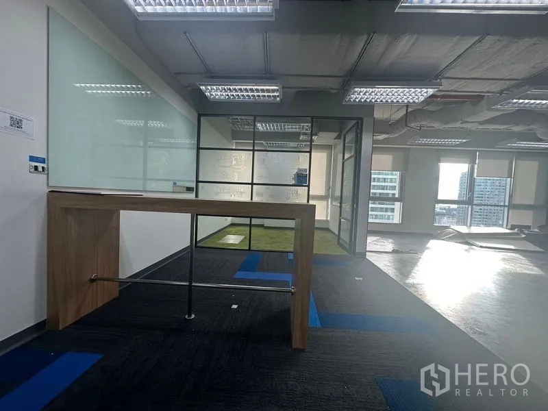 办公空间 出租在Bang Rak, Bangkok - 玻璃会议室旁的高桌，落地窗可看城市景观。