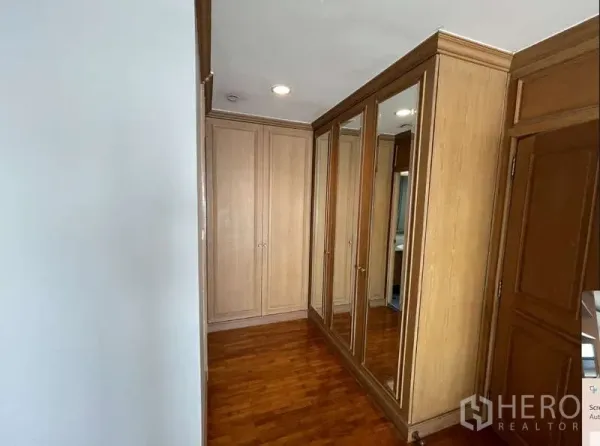 Condominium for rent - Walk-in closet corridor featuring full-height mirrored wardrobes and wood cabinetry.