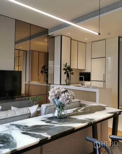 Condominium for rent in Khlong Toei, Bangkok - Long marble dining counter with linear pendant light beside built-in kitchen