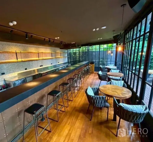 Retail Space for rent in Yan Nawa, Bangkok - Long cocktail bar with stools, round dining tables, and full-height windows to the green courtyard.