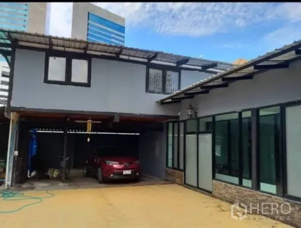 独立式住宅 出租在Khlong Toei, Bangkok - 两层住宅外观，带车棚与城市高楼背景