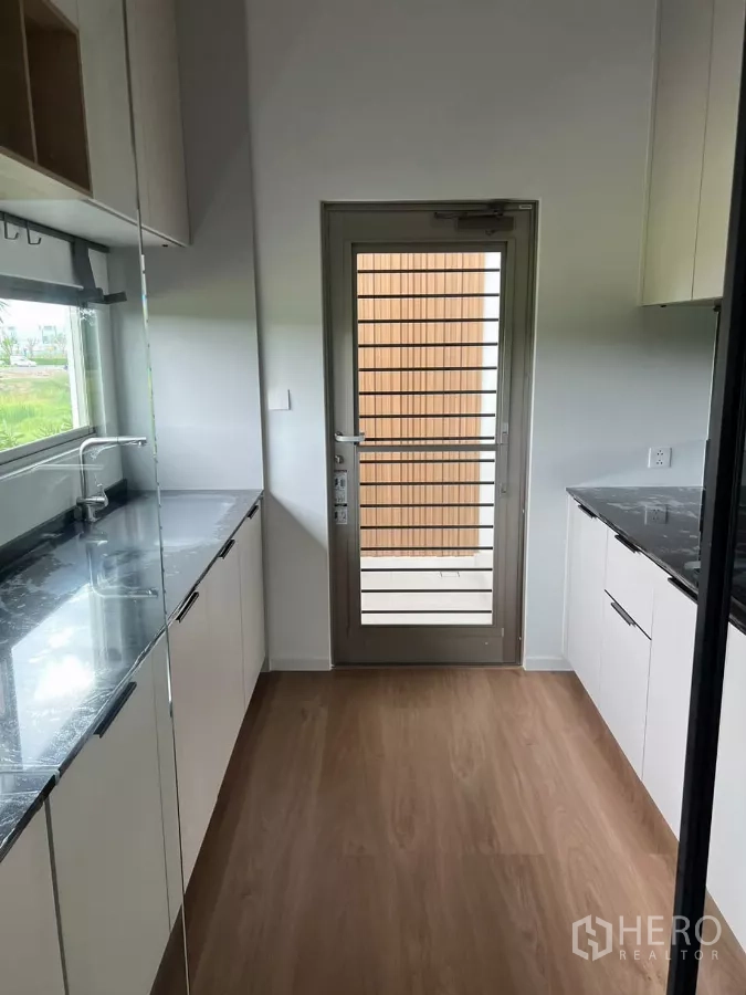 Detached House for rent in Saphan Sung, Bangkok - Secondary galley kitchen with twin counters, marble-look tops and a rear door.