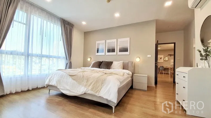 Condominium for rent in Khlong Toei, Bangkok - Spacious master bedroom with floor-to-ceiling windows, king bed, bedside lamps and wood flooring.