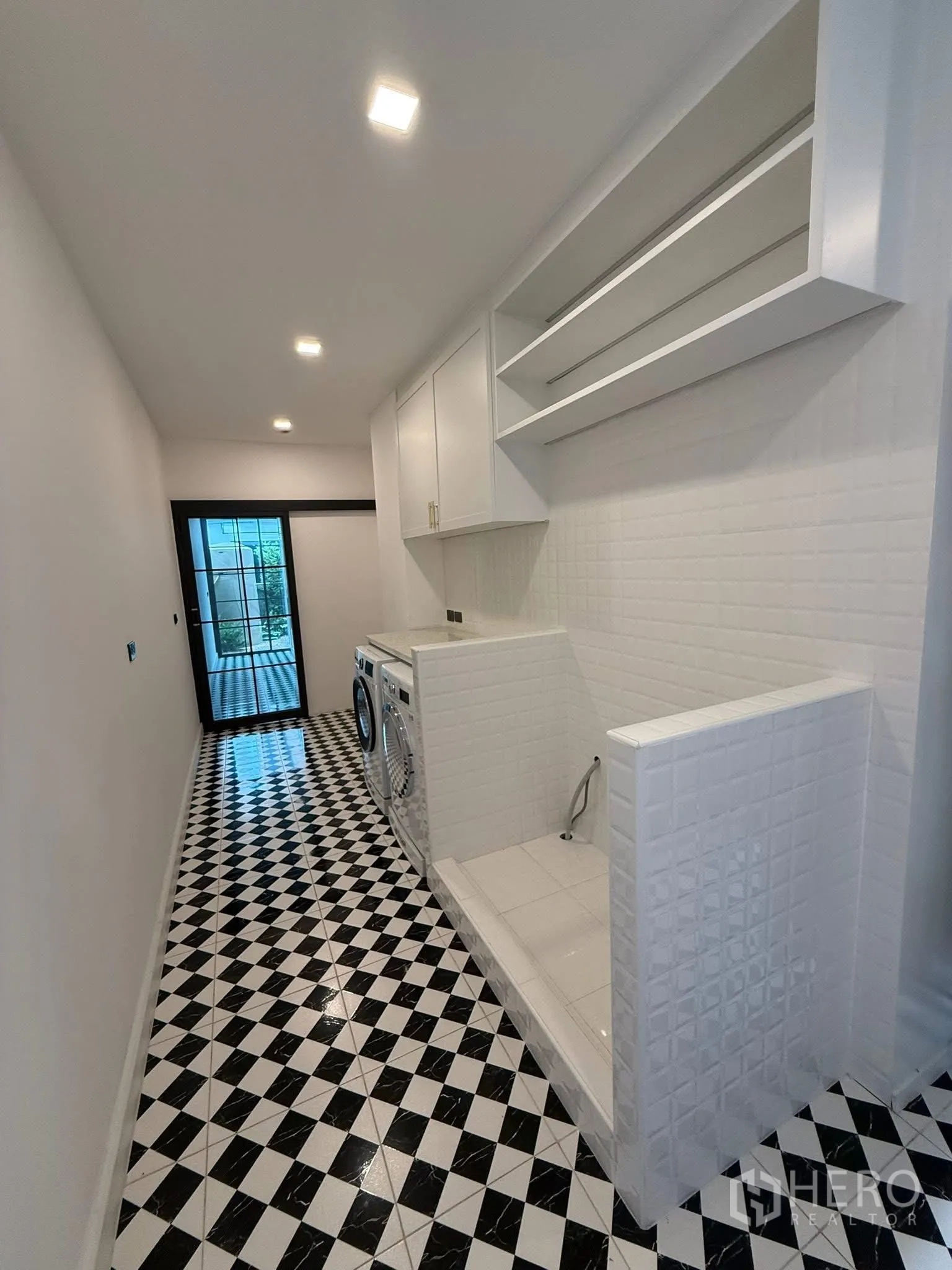 Detached House for sale in Bang Kruai, Nonthaburi - Laundry room with washer and dryer, utility sink and checkered floor leading to rear door.