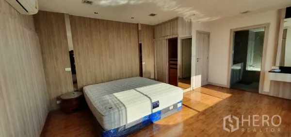 公寓 出租在Khlong Toei, Bangkok - 采光充足的主卧，木地板、木纹墙面，并可通往套内卫浴。