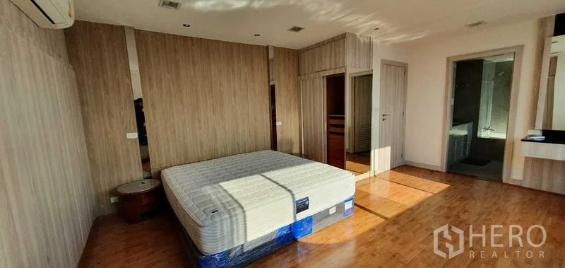 公寓 出租在Khlong Toei, Bangkok - 采光充足的主卧，木地板、木纹墙面，并可通往套内卫浴。