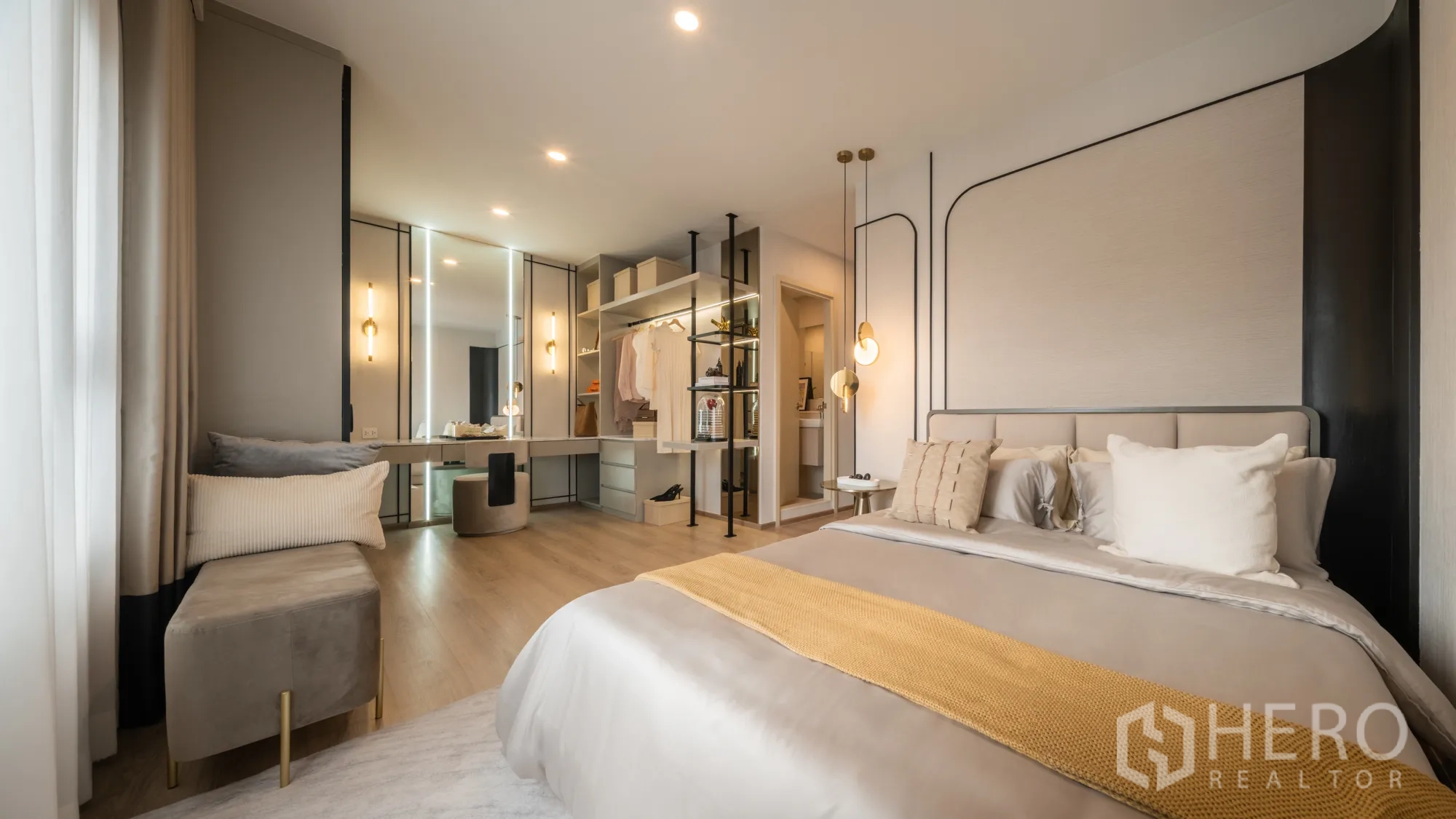Condominium for sale in Khlong Toei, Bangkok - Primary bedroom with open wardrobe, mirrored vanity, and soft pendant lighting.