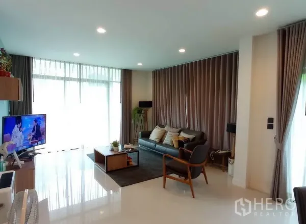 独立式住宅 出租在Bang Kapi, Bangkok - 采光充足的客厅，落地窗、筒灯、沙发与电视柜。