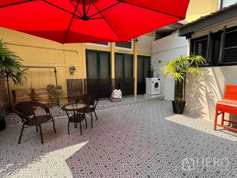 Townhouse for rent in Ratchathewi, Bangkok - Courtyard terrace with laundry area, large red parasol, seating and potted palms.