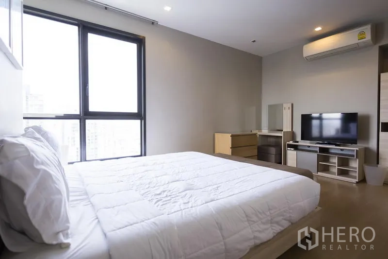 公寓 出租在Watthana, Bangkok - 主卧配特大床、大窗、电视柜、空调与内置收纳。