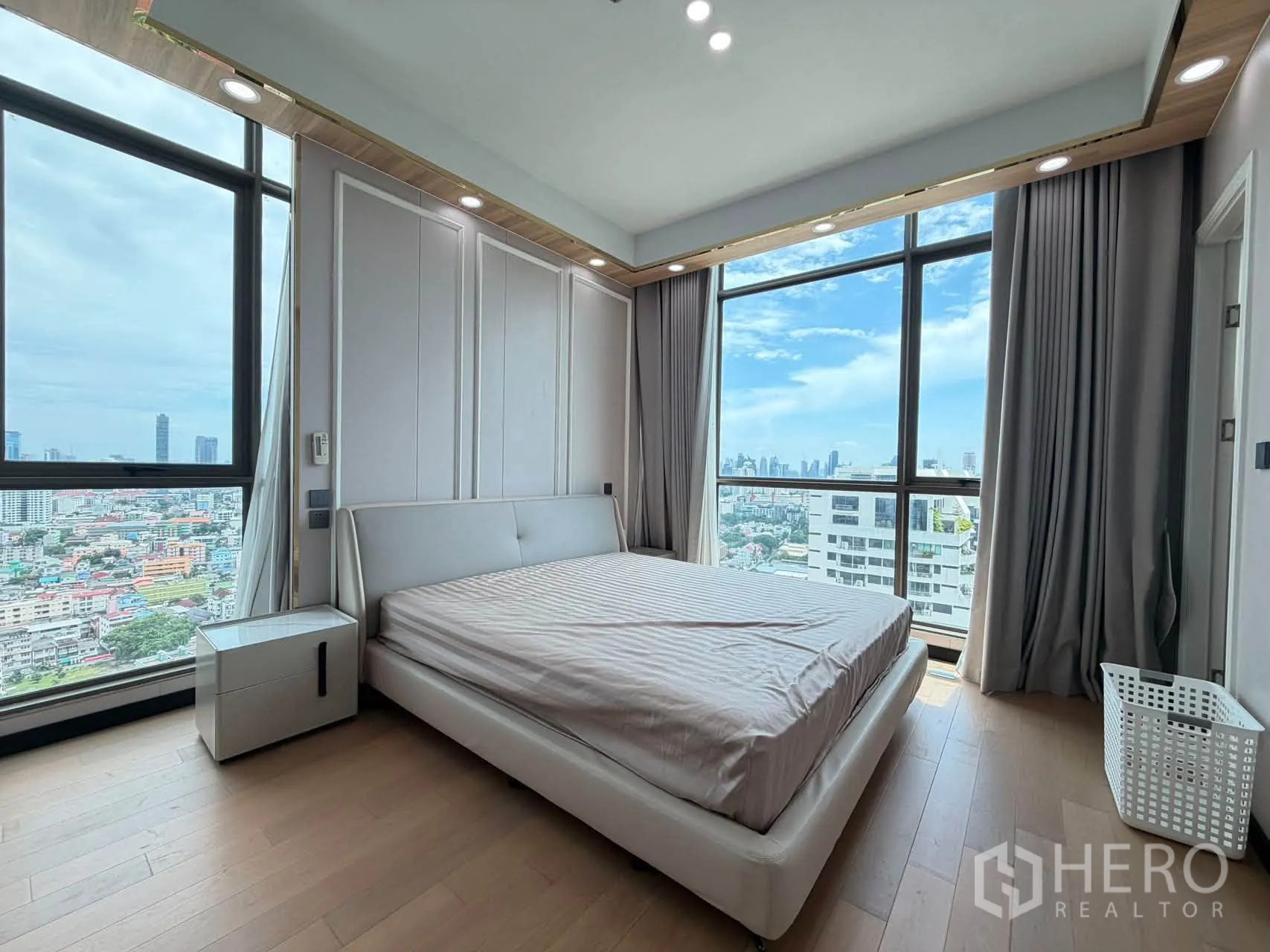 Condominium for sale in Watthana, Bangkok - Corner bedroom with wide city skyline views and contemporary bed.