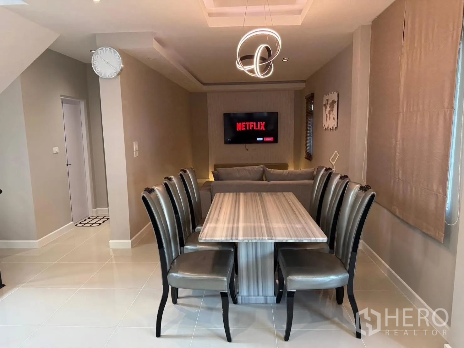 独栋房屋 for rent in Prawet, Bangkok - 餐厅设八人餐桌与艺术吊灯，旁为带壁挂电视的休闲区